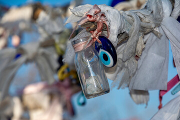 A glass bottle and evil eye amulet hanging from a tree branch in Turkey.