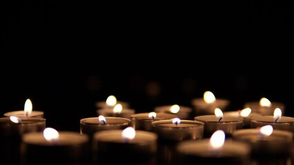 Many candles burn in the dark. Memorial day with candles. Lighted memorial candles. Funeral candles close-up.