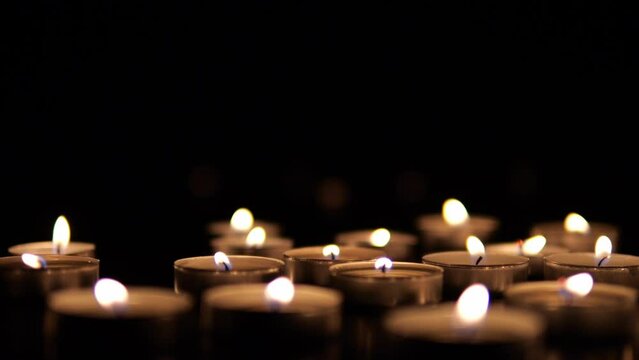 Many candles burn in the dark. Memorial day with candles. Lighted memorial candles. Funeral candles close-up.
