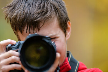 Close-up of boy looking through camera with big lens