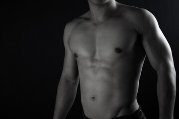 Fototapeta na wymiar Close up view of sexy body of young man with six pack muscular and athletic body on black background. concept of health care, exercise, fitness, muscle mass, health supplements.
