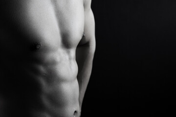 Fototapeta premium Close up view of sexy body of young man with six pack muscular and athletic body on black background. concept of health care, exercise, fitness, muscle mass, health supplements.