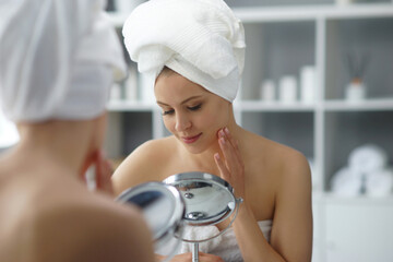 Young woman sits in the bathroom in front of the makeup mirror and does cosmetic procedures....