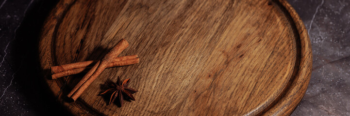 Banner round wooden tray with a dark finish sits on a dark background resembling marble. The...