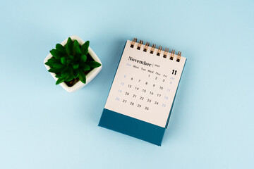 November 2023 desk calendar with potted plant on blue background