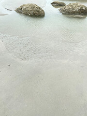 a serene beach and small rocks. The clear blue sea and sky make for a perfect summer landscape, perfect for travel and tourism. Relax and enjoy the calming atmosphere of this coastal paradise