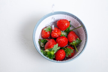 Water pouring into bowl with red strawberries