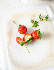 sliced ​​strawberries and whole strawberries on cutting board, kitchen tools in background