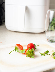 sliced ​​strawberries and whole strawberries on cutting board, kitchen tools in background