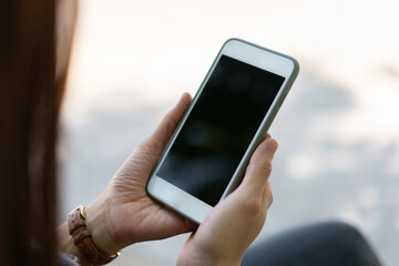 Close up hand of technology in use . Businesswoman typing on smart phone with hand finger touch screen, texting, chatting or social media on street
