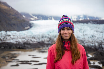 portrait of a beautiful Icelandic girl wearing a colorful wool Icelandic hat with a powerful glacier in the background