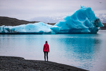 A girl wearing an Icelandic wool cap admires the unique blue icebergs on Lake Jökulsárlón, a...