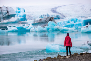 A girl wearing an Icelandic wool cap admires the unique blue icebergs on Lake Jökulsárlón, a unique glacial lake at the Vatnajökull glacier