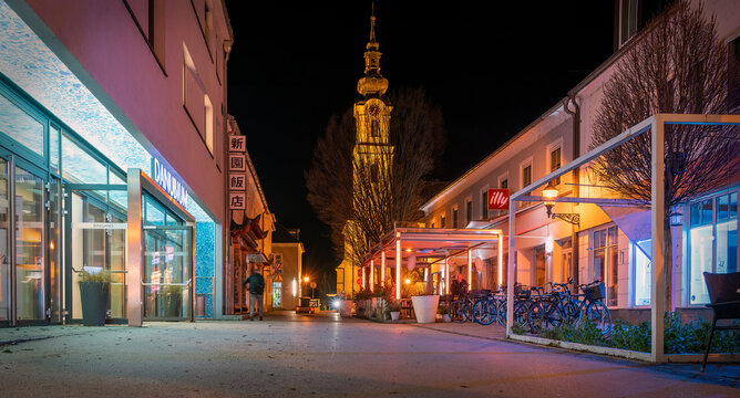 view across the "Br&uuml;dergasse" with entrance to the event location "Danubium" and the tower of the Friars Minor Conventual Church in Tulln at the river Danube at night, Austria
