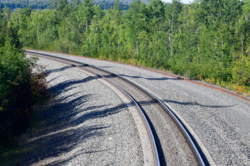 Long empty railroad track rails through the forest parks in Alaska