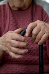 the hands of an elderly woman feed on a wooden cane. The concept of the life of the elderly, care and acceptance of age