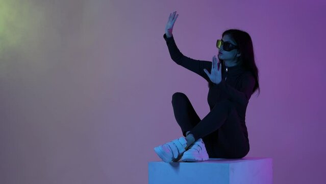 Woman in futuristic costume. Female in modern VR glasses interacting with network while having virtual reality experience. Augmented reality game, future technology, AI concept. VR. Neon light. - Powered by Adobe