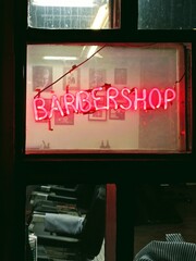 On the glass is a glowing neon red sign that reads “BARBERSHOP