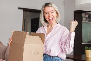 woman sitting on couch at home opening carton box received parcel package