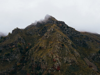 Landscape scenic drone photo of  the mountain covered trees in autumn colors in a fog, grass and different rocks