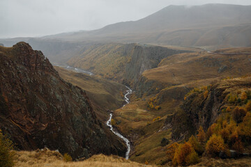 Photo of the gorge with mount river in it in Autumn foggy and cloudy day. Photo taken on Djily-Su road, it's popular tourist place in Kabardino-Balkaria, Russia