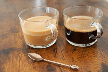 Cups of latte and black coffee with capsules on brown wooden table
