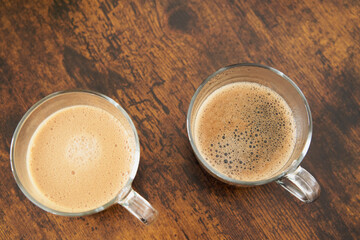 Cups of latte and black coffee on brown wooden table