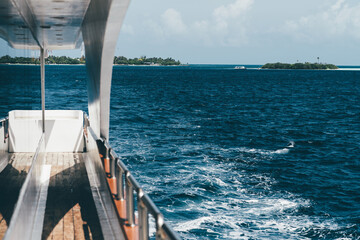 A shot of a peaceful journey on a yacht sailing on the warm seawater. The breathtaking scenery of the surrounding blue sea and the islets in the back create an idyllic setting with clouds in the sky