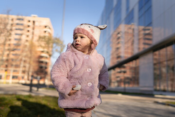 Small caucasian girl toddler stand in the city outdoor in winter day