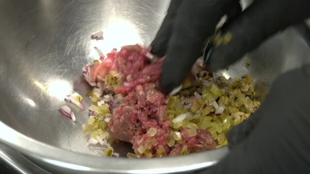 fresh beef tartar dish with tasty vegetables. Delicious tartare made of raw beef and served with onions and pickled cucumbers