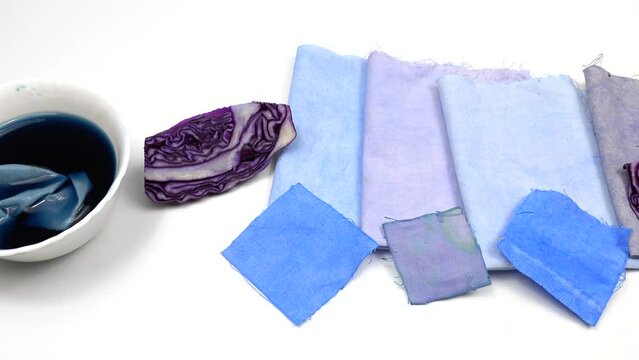 Bowl with decoction of red cabbage and samples of cotton fabric with gradient in blue tones, background.  Natural dyeing for fabrics, DIY
