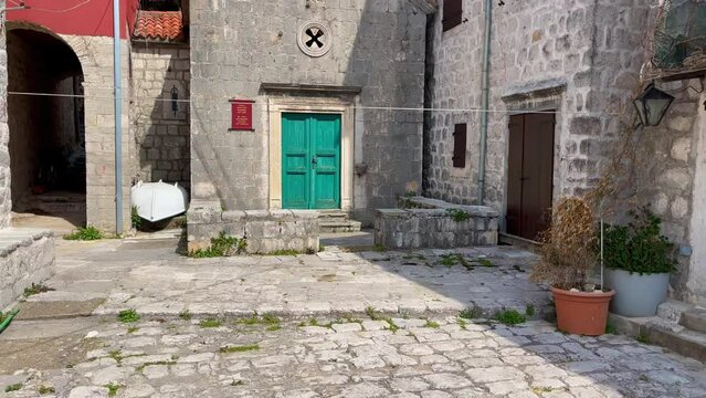 Walking through the charming coastal town of Perast in Montenegro. Strolling along its cobblestone streets lined with historic buildings, including a stunning cathedral with a towering bell tower