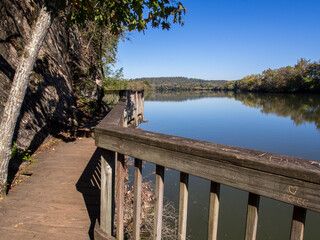 Walkpath by the blank water (Tennesse River) and clear blue sky in Ijams Nature Center, Knoxville, Tennessee, USA. - obrazy, fototapety, plakaty