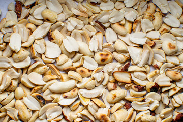Roasted peanuts separated in two pieces and spread over surface.