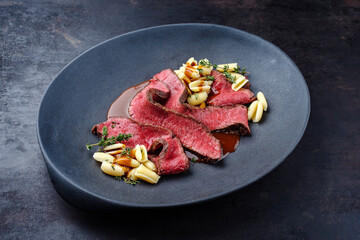 Traditionelles italienisches Chianina Roastbeef mit Gnocchetti-Sardi Nudeln in würziger Rotweinsoße serviert als close-up auf einem Design Teller mit Textfreiraum 