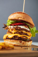 Loaded cheeseburgers three triple, stacked patties stacked high with layers of cheese, lettuce, and...