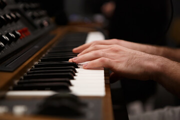 Fototapeta na wymiar Hands of pianist playing music on synthesizer. Professional synth device keyboard in close up