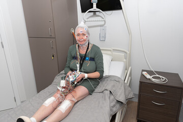 Middle aged woman measuring brain waves, examining polysomnography in sleep lab