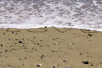 sea wave washing away word Love written on beach sand