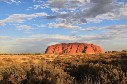 Late afternoon view of Uluru Ayers Rock under warm light-mostly cloudy sky. NT-Australia-478