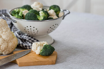 Fresh green broccoli and cauliflower on a wooden chopping board on a linen tablecloth. Broccoli cabbage leaves. Light background. Vegetarian food. Healthy lifestyle.