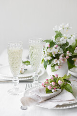 Beautiful table decor for a wedding dinner with a spring blooming apple tree flowers. Celebration of a special event. Fancy white plates, wineglasses