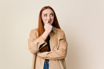 Young red hair woman isolated relaxed thinking about something looking at a copy space.