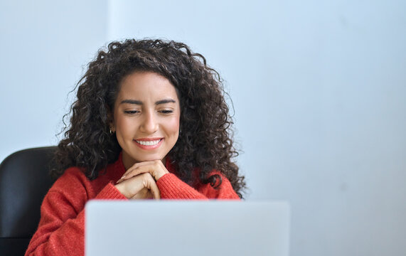 Young Happy Latin Business Woman Office Worker Student Using Laptop Having Remote Virtual Work Meeting Call In Office Or Watching Online Webinar, Elearning, Remote Learning Course Looking At Computer.