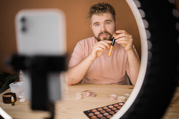 Male beauty blogger doing his make up and recording a video lesson his with mobile phone - vlog,...