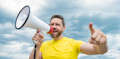 man in yellow shirt shout in loudspeaker on sky background. communication