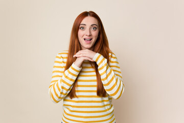 Young red hair woman isolated praying for luck, amazed and opening mouth looking to front.