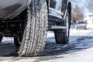 Gros plan d'un pneu d'hiver sur rue partiellement enneigée