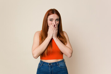 Young red hair woman isolated laughing about something, covering mouth with hands.