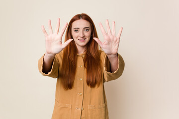 Young red hair woman isolated showing number ten with hands.